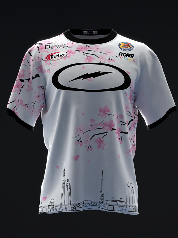 White bowling jersey with pink cherry blossoms, black oval logo, and cityscape graphic
